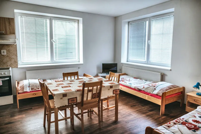 Pokoj apartmánu s postelemi, jídelním stolem a kuchyňkou